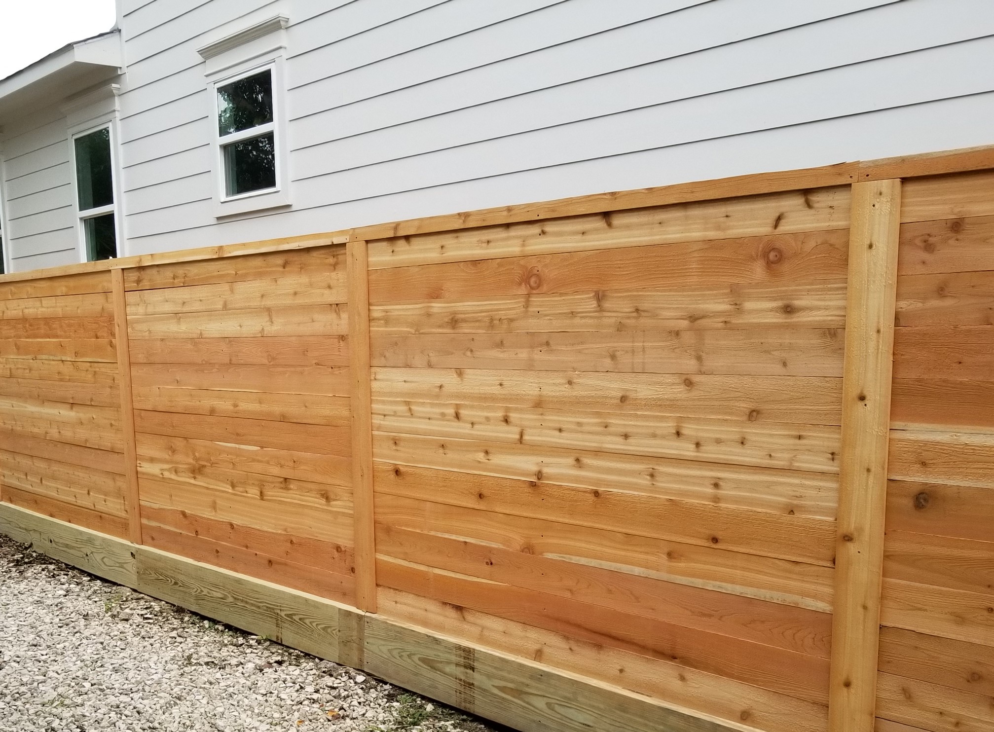 Horizontal privacy fence with 2x12 pressure treated rot board and cedar pickets.